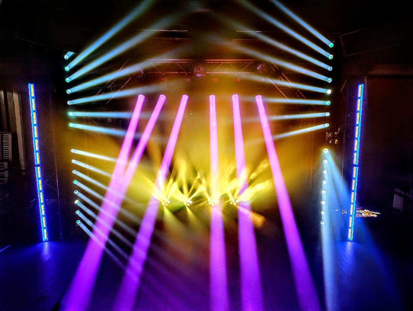 Magenta and amber lighting beams cutting through haze over a stage