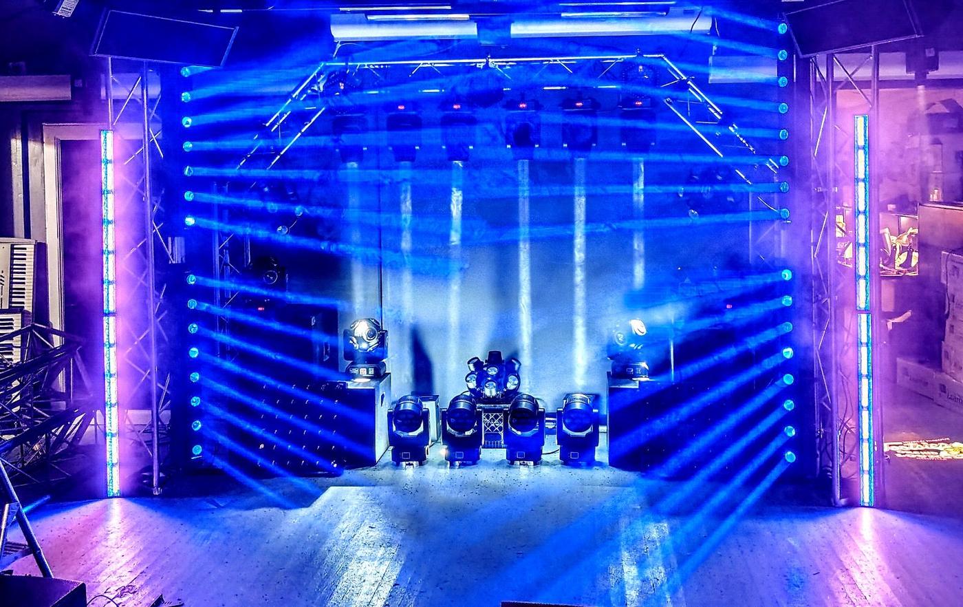 Blue and purple stage lighting rig with LED tube towers and moving heads